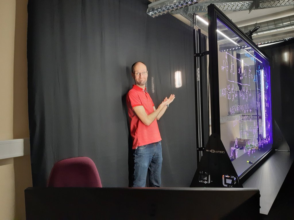 Autor hinter Lightboard; zeigt auf störenden Lichteinfall