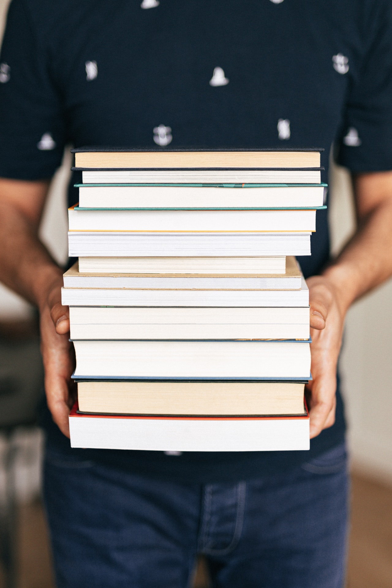 Eine Person hält einen Stapel Bücher