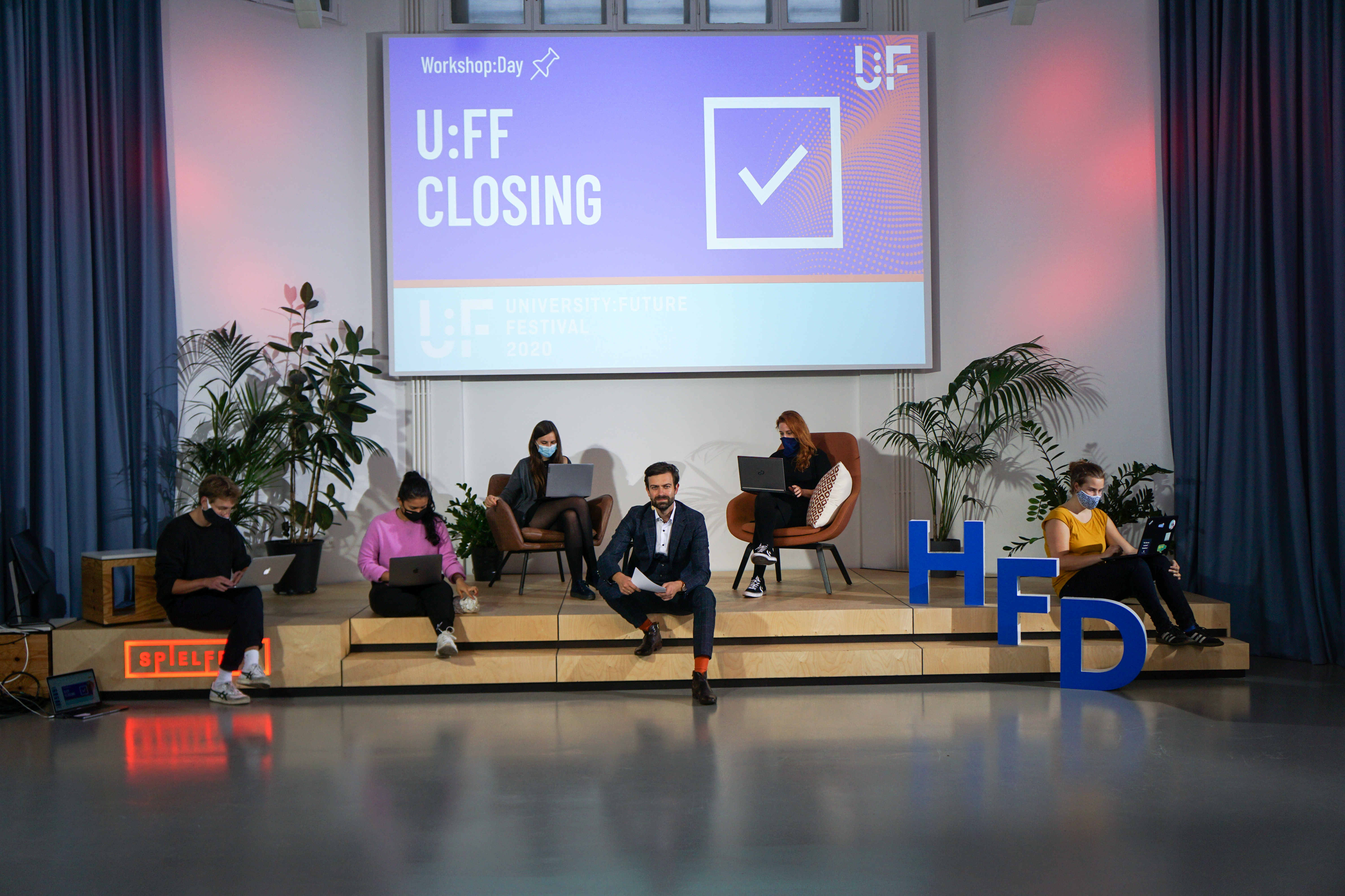 6 members of the event team with masks sitting on a stage at their laptops