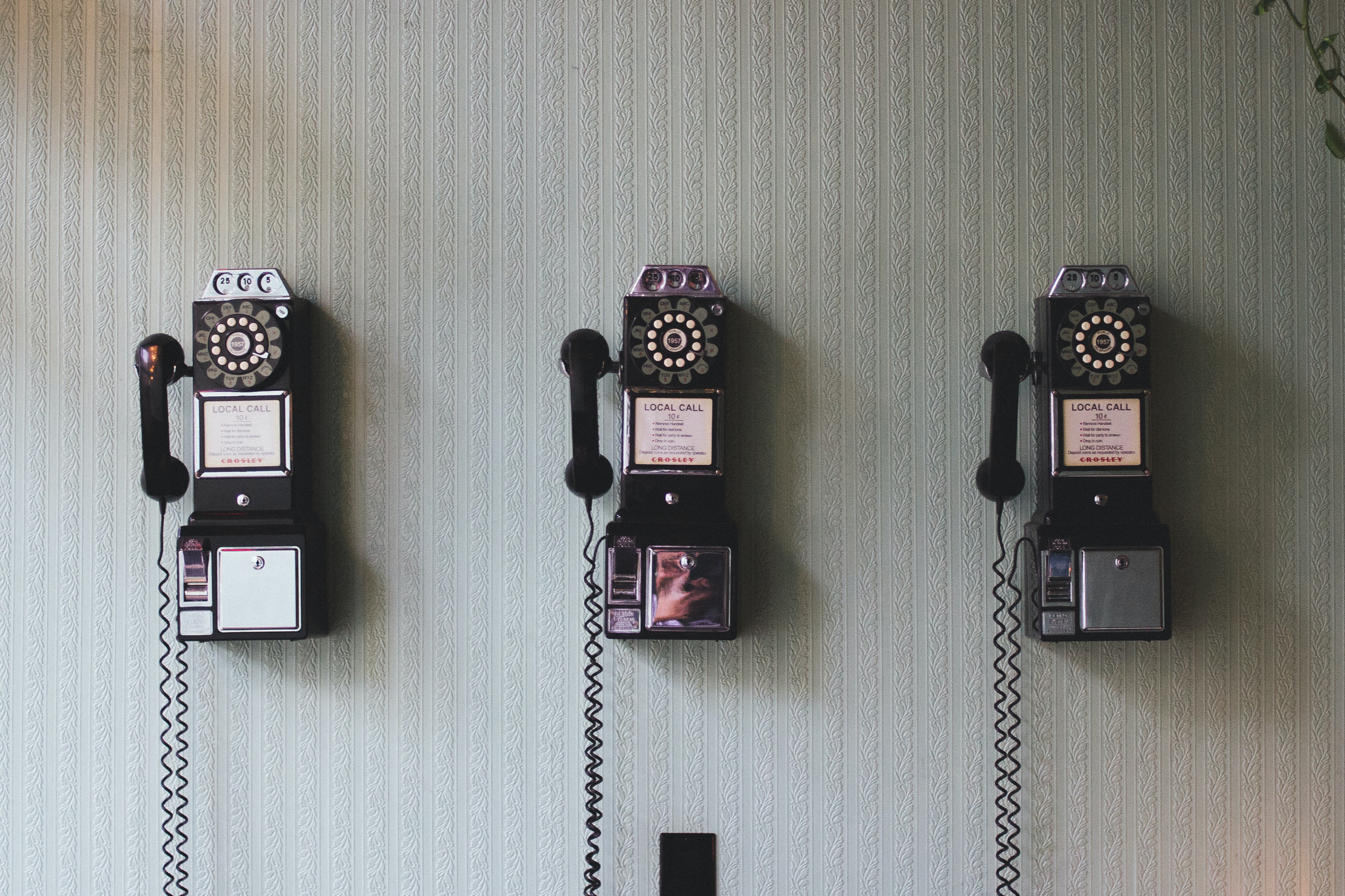 Drei Wandtelefone mit Wählscheibe nebeneinander