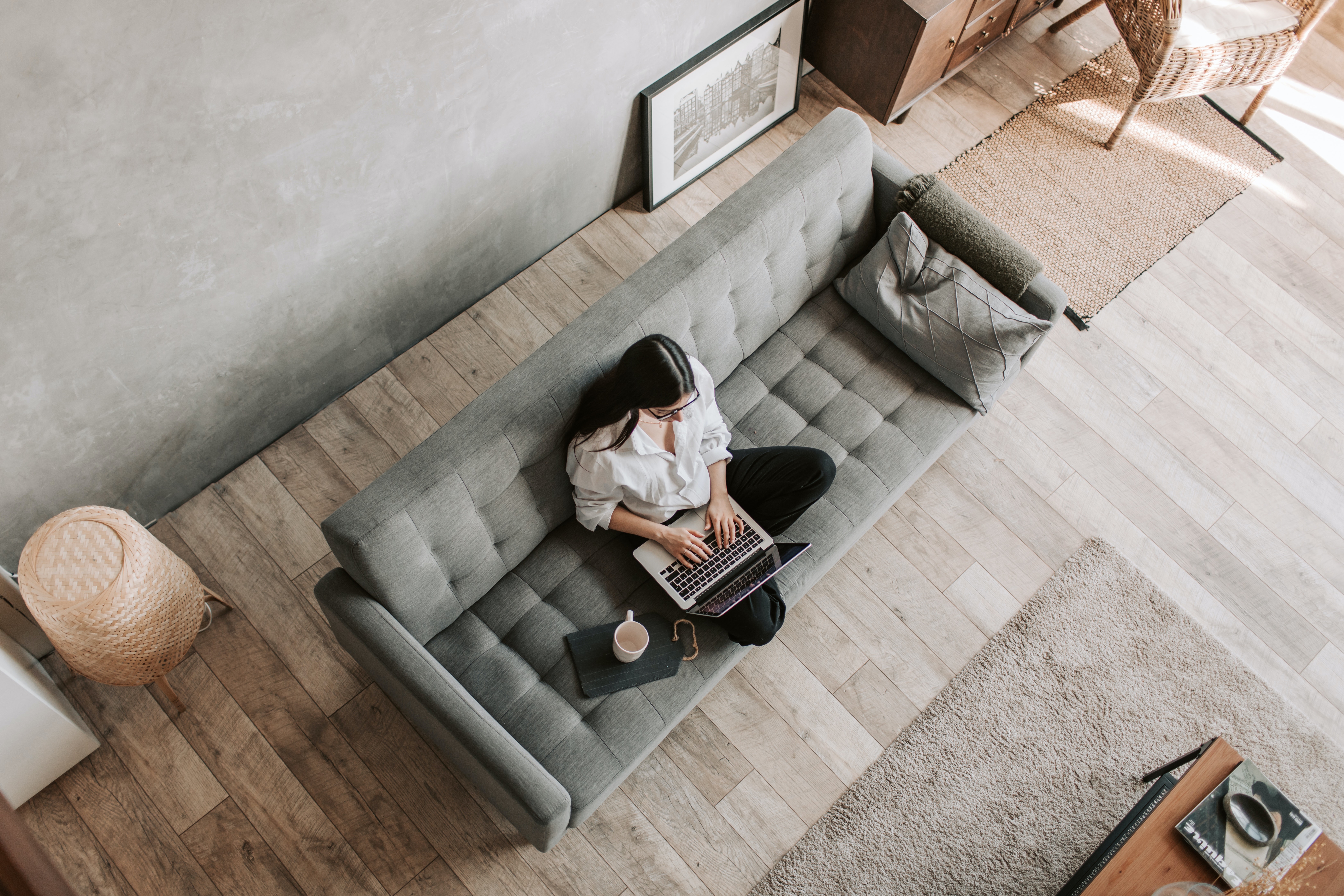 Eine Person sitz auf einer Couch und arbeitet von Zuhause.