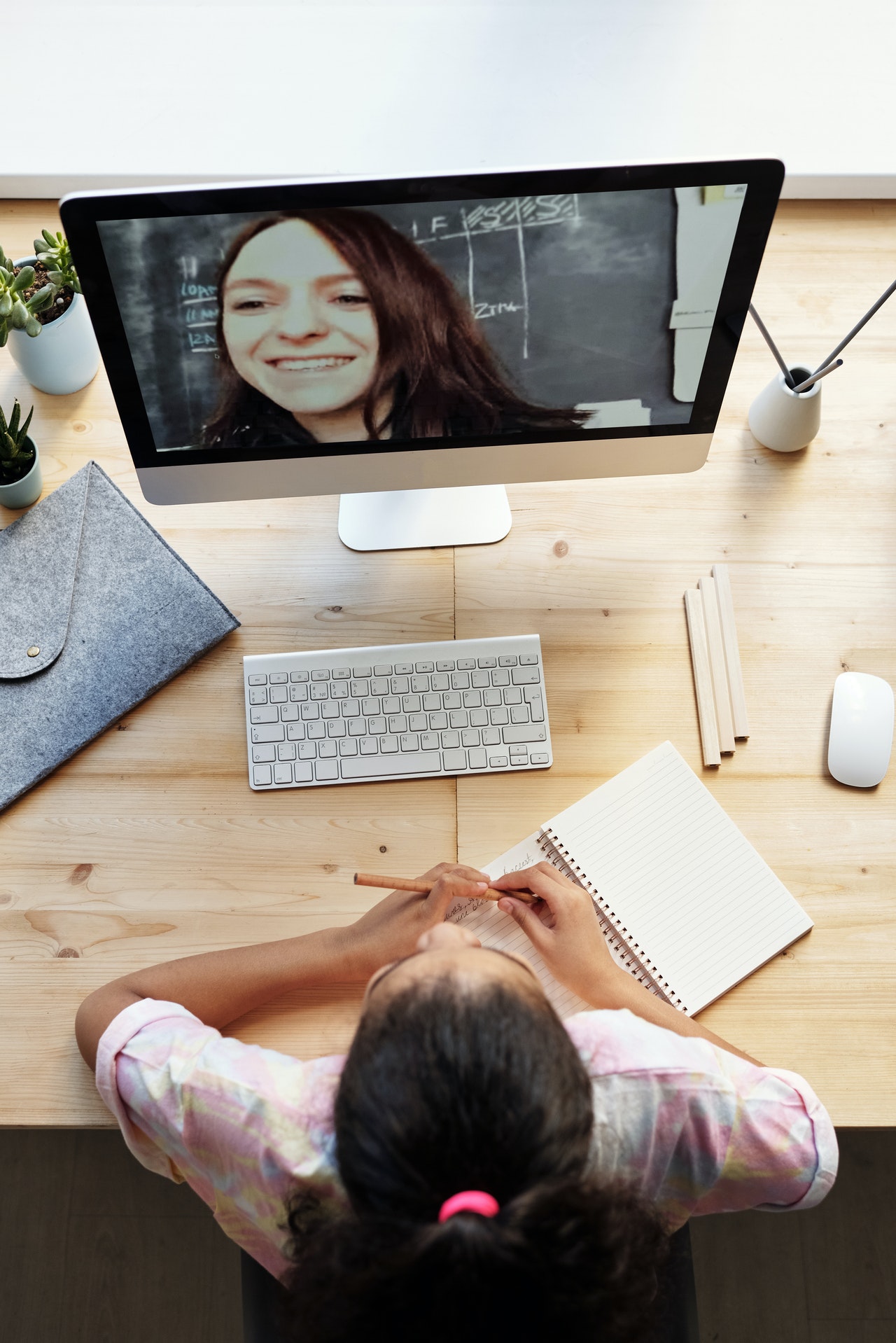 Girl from bird's eye view in front of computer in a video conversation with young woman